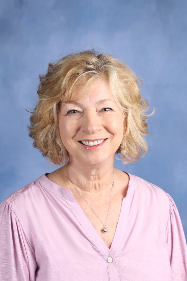 Tetyana Horoian smiling in a portrait with a blue background.