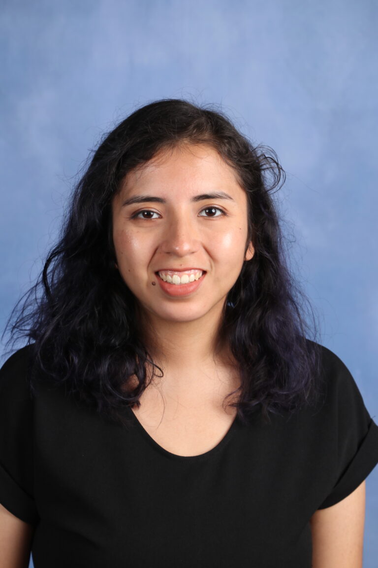 Portrait of Tetyana Horoian smiling with dark hair against a blue background.