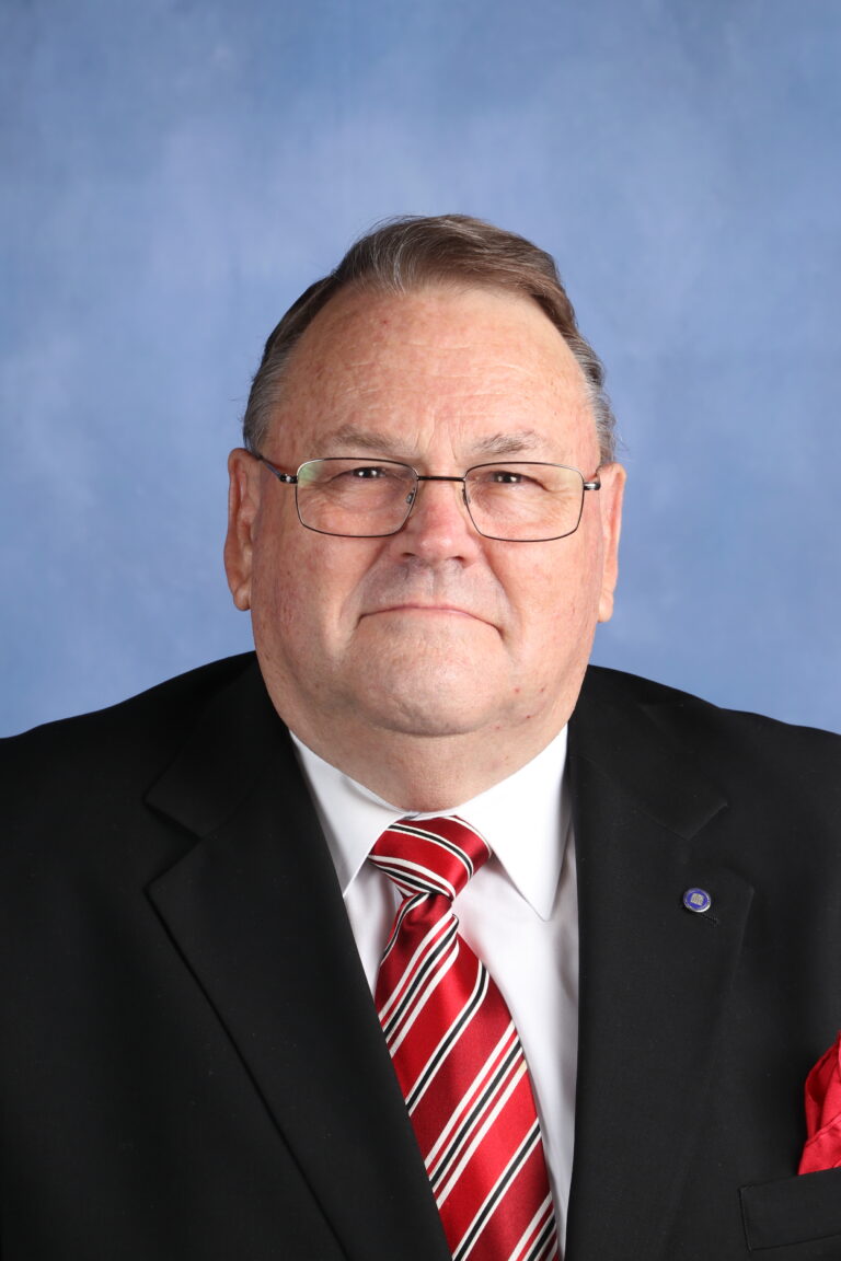 Portrait of Tetyana Horoian in a suit and tie against a blue background.