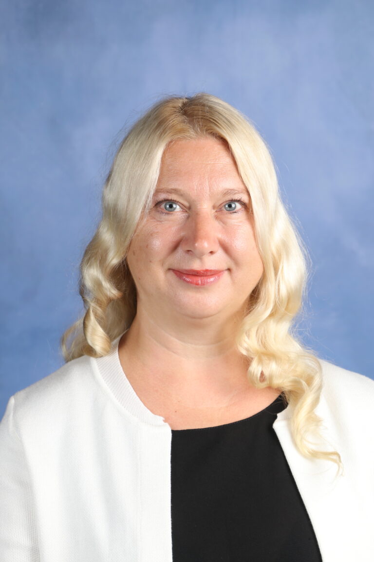 Tetyana Horoian, blonde woman with blue eyes, wearing a white jacket.