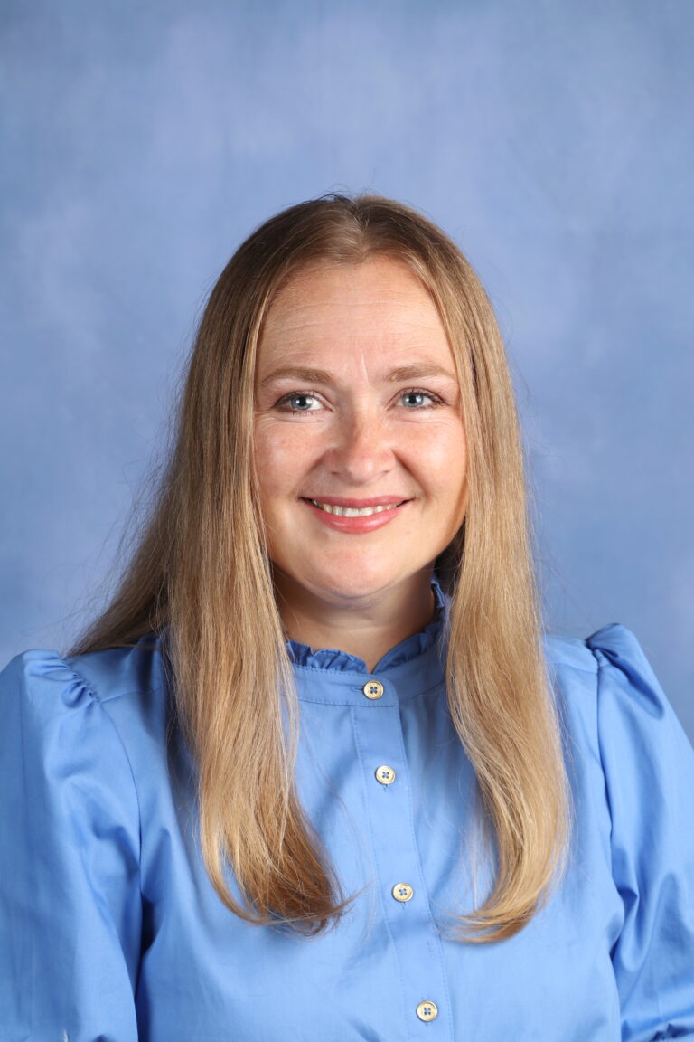 Tetyana Horoian portrait; woman with long blonde hair smiles against a blue background.