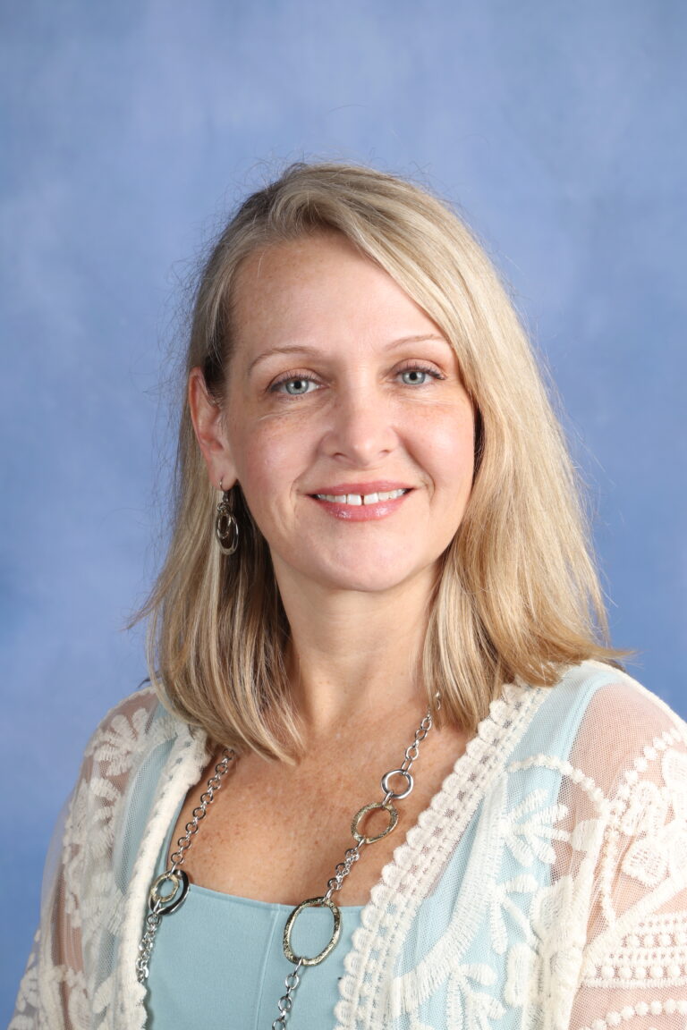 Tetyana Horoian, smiling woman with blonde hair, wearing a light blue top and white lace cardigan.