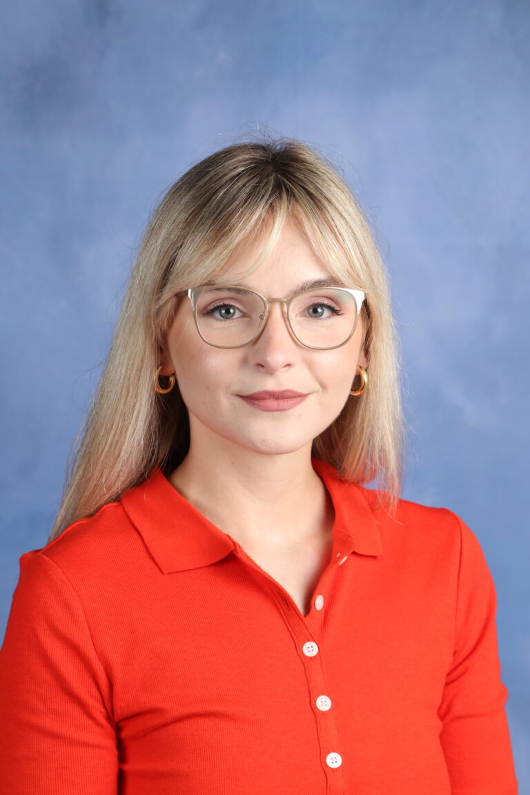 Tetyana Horoian portrait with blonde hair and glasses, wearing an orange shirt.