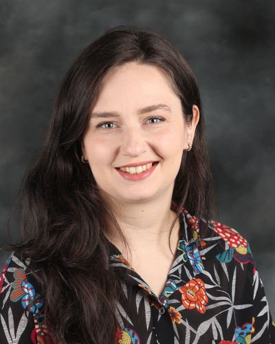 Portrait of Maryna Medova, smiling with dark hair and a patterned shirt.