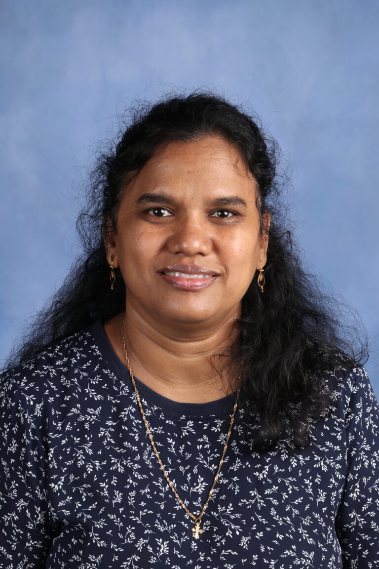 Patricia Soundrapandian, smiling in a headshot with a blue patterned shirt and gold jewelry.