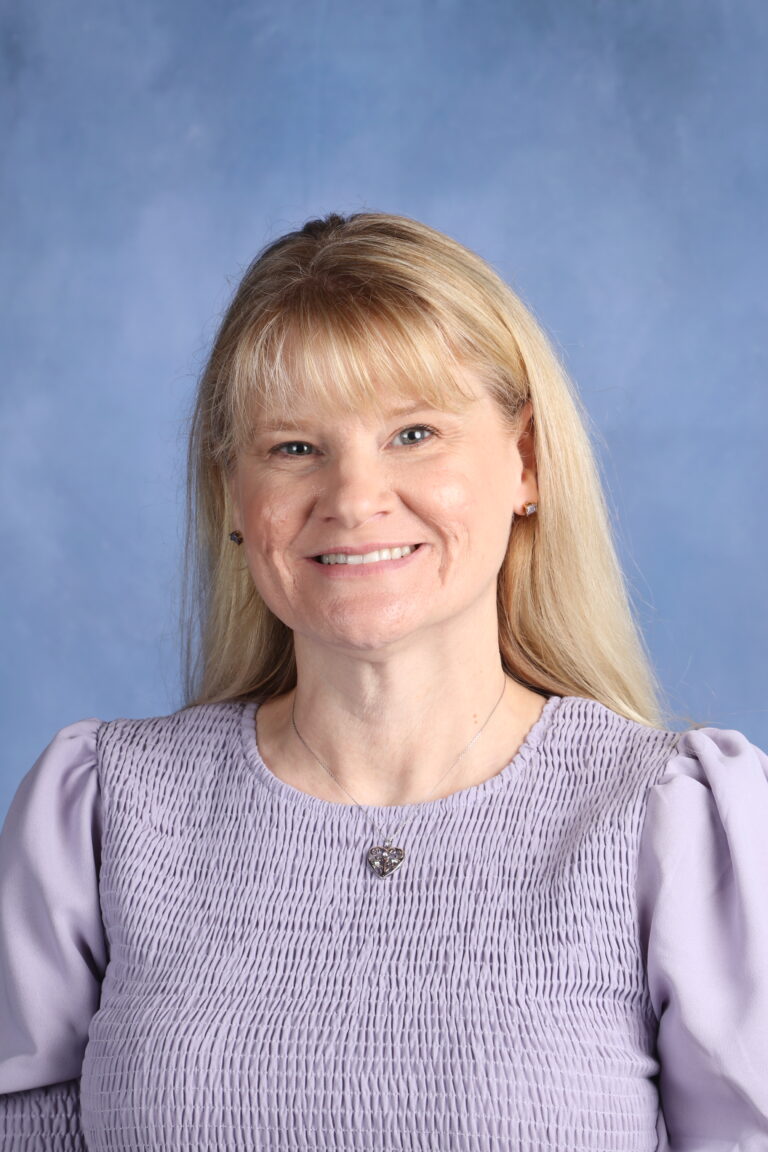 Eugenia Collett headshot. Smiling woman with blonde hair and purple top.